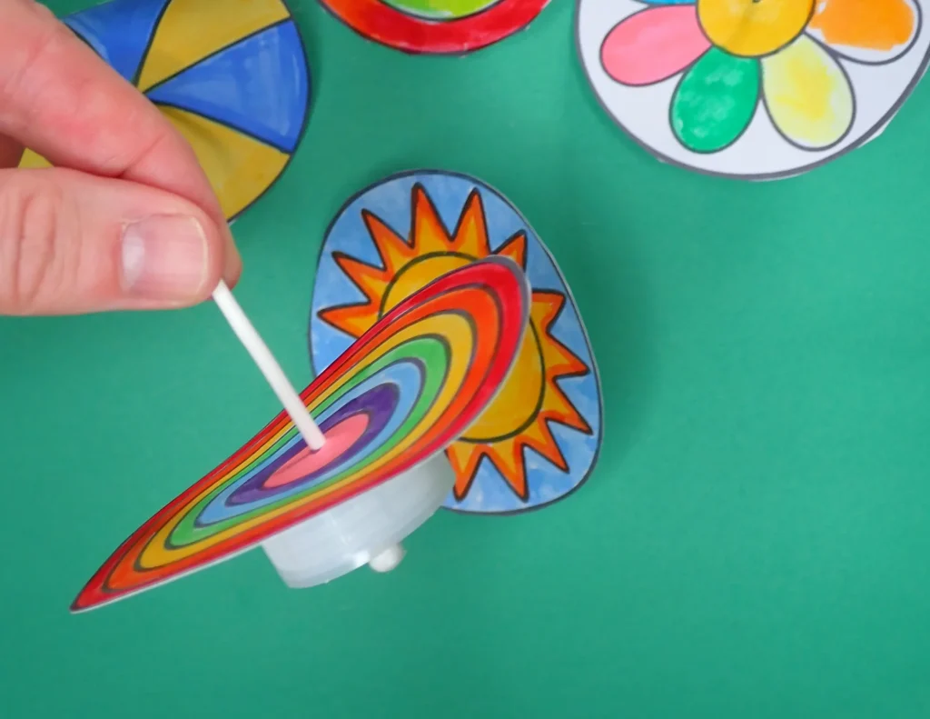 Spinning top toy made with bottle lid, cotton swab and paper top