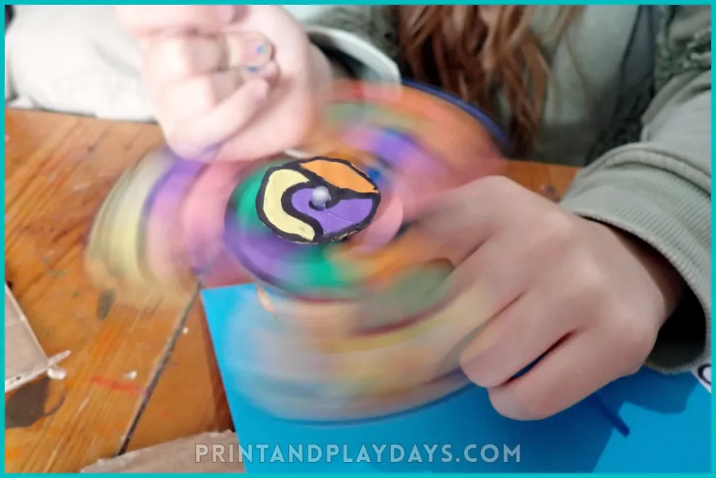 child showing a cardboard fidget spinner spinning